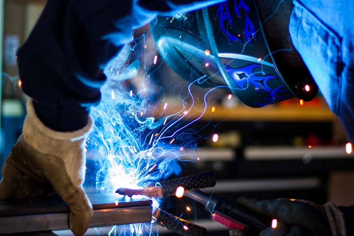 A welder joining steel amid bright sparks in a workshop